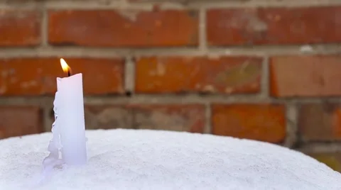 Candle on snow against brick wall. Christmas holidays background Stock Footage 66439409