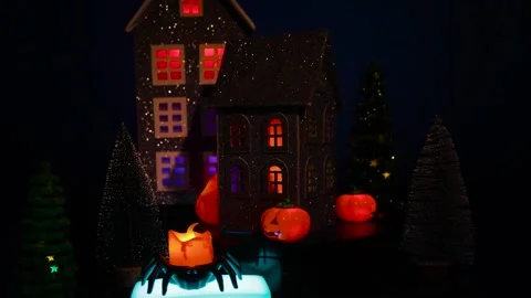 Candle in a spider-shaped candlestick on a stand against of a Halloween village Stock-Footage 319293492
