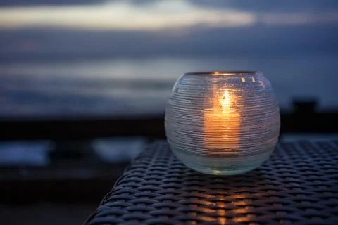 Candle on a table with beach view at sunset Stock Photos