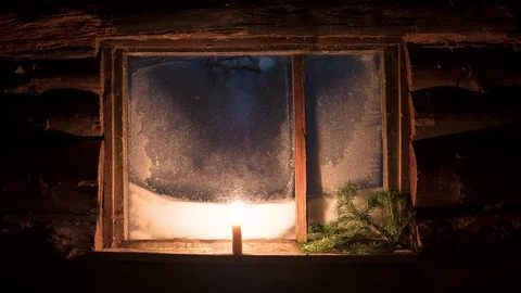 A candle thaws the frozen window of a small log house 4K timelapse 動画素材 77147041