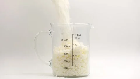 Candle wax flakes being poured into glass measuring jug Stock Footage 344743054