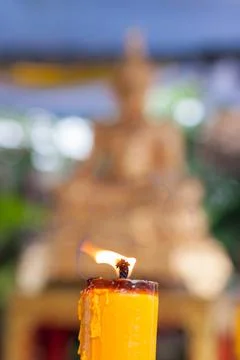 Candlelight burning in front of Buddha statue. Focus on candle frame, buddha Stock Photos