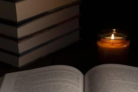 Candlelight study scene with open book and stacked books Stock Photos