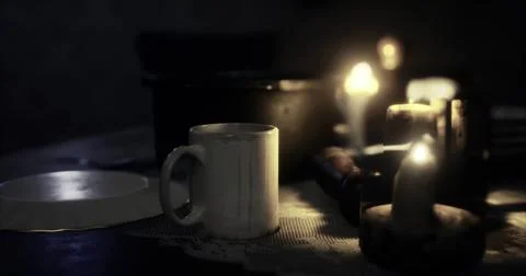 Candlelit table setting with a mug, plate, and wooden objects at dusk Illustrazione stock