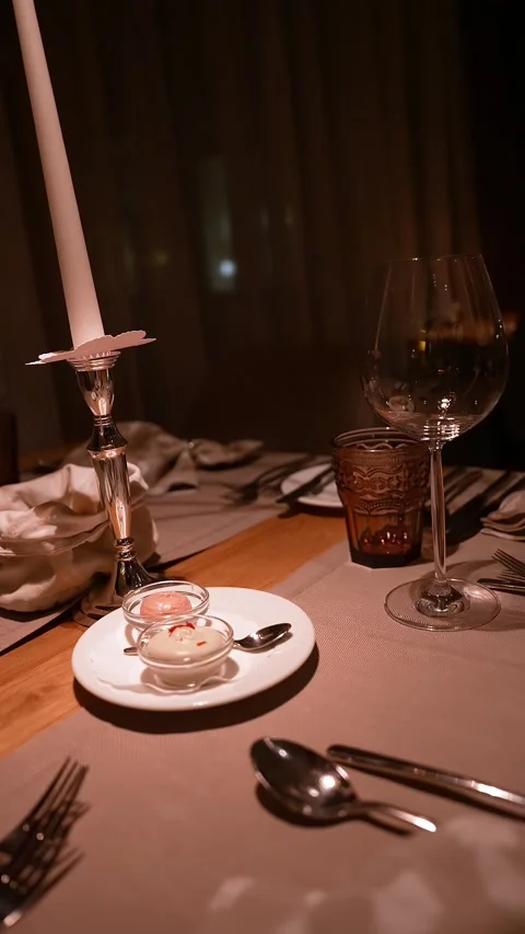 Candlelit table setting with wine glass and amber tumbler at dinner Stock Footage 331958017