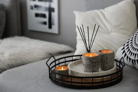 Candles and aroma reed diffuser on grey sofa, space for text Stock Photos