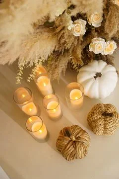Candles and decorative items on a table with dried plants and white pumpkin.. Stock Photos