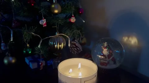 Candles burn and glow on the table next to the Cristmas tree 動画素材 326339639