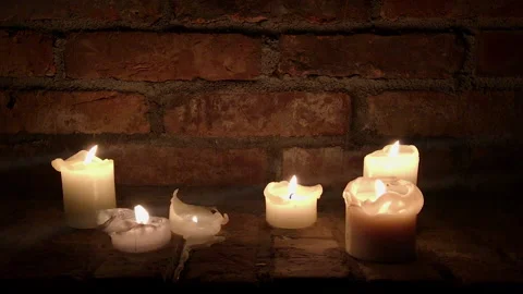 Candles burn in the dark on a brick wall background Stock Footage 145014952