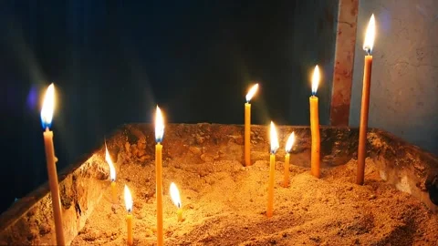 Candles burning brightly in sand, creating a serene atmosphere in a dim room Stock Footage 330931175