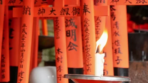 Candles burning in small temple with red torii at the background Stock Footage 132835765