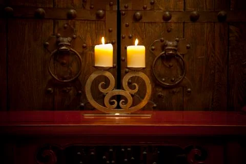 Candles burning on table in front of old rustic door Stock Photos