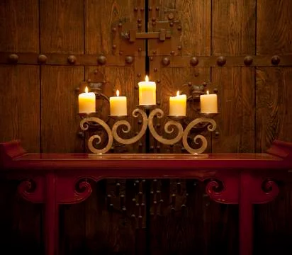 Candles burning on table in front of old rustic door Stock Photos