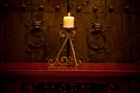 Candles burning on table in front of old rustic door Stock Photos