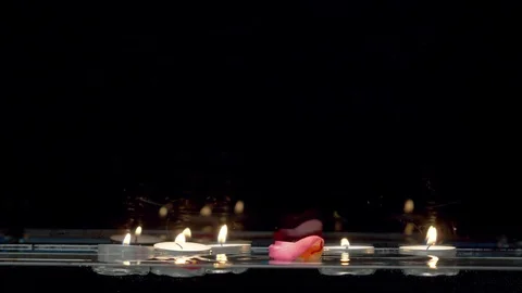 Candles floating on the water and falling rose petals Stock Footage 123577963