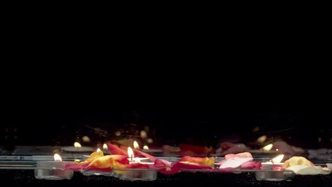 Candles floating on the water and falling rose petals Stock Footage 123578060