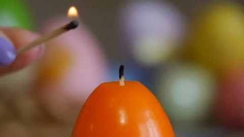 Candles made in shape of easter egg. Orange candles. Female hand lights candles. Stock Footage 106147476