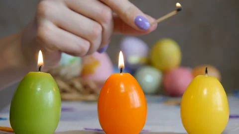 Candles made in shape of easter egg. Green, orange, yellow. Female hand lights Stock Footage 106147561
