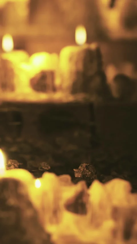 Candles provide light in a dim setting with natural elements on the ground Stock Footage 334260590