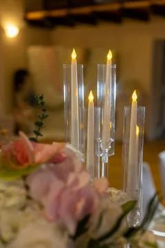 Candles sit in clear holders on a table filled with flowers. This scene happe 库存照片