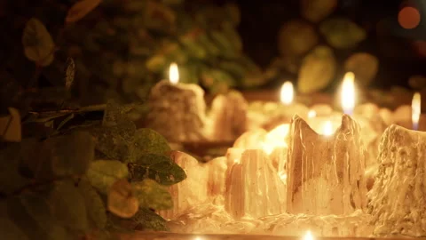 Candles sit on a wooden table surrounded by plants during an evening gathering Video stock 340234079