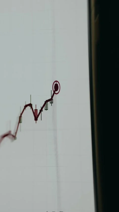 Candlestick price chart displaying a red trend line and glowing indicator point Stock Footage 334941424
