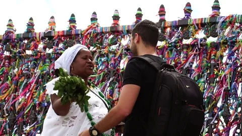 Candomble woman wearing traditional clothes at Bonfim Church blessing a tourist Stock Footage