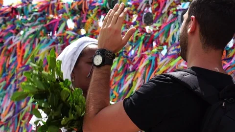 Candomble woman wearing traditional clothes at Bonfim Church blessing a tourist Stock Footage