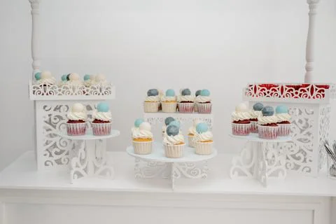 Candy bar with white and red cupcakes decorated with cream and fondant balls Stock Photos