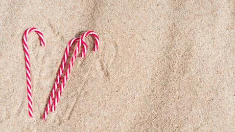 Candy cane on the sandy beach. new year and xmas vacation in hot countries at Stock Photos