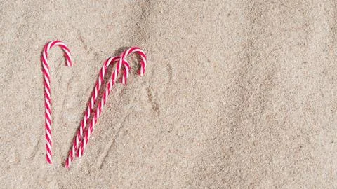 Candy cane on the sandy beach. new year and xmas vacation in hot countries at Stock Photos