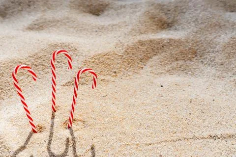 Candy cane standing on white textured sandy background. Stock Photos