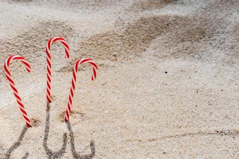 Candy cane standing on white textured sandy background. Stock Photos