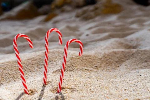 Candy cane standing on white textured sandy background. Stock Photos