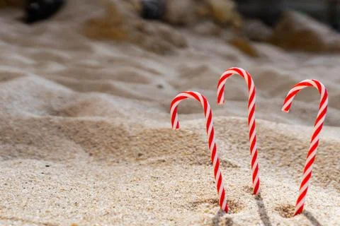 Candy cane standing on white textured sandy background. Stock Photos