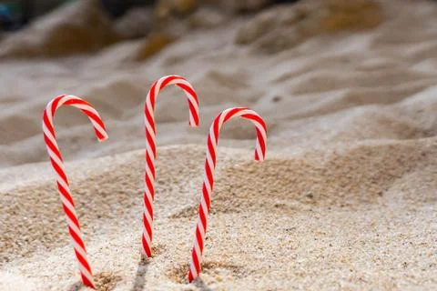 Candy cane standing on white textured sandy background. Stock Photos