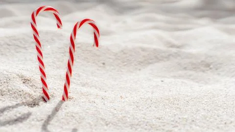 Candy cane standing on white textured sandy background. Stock Photos