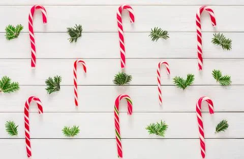 Candy canes and pine branches on white wooden background Stock Photos