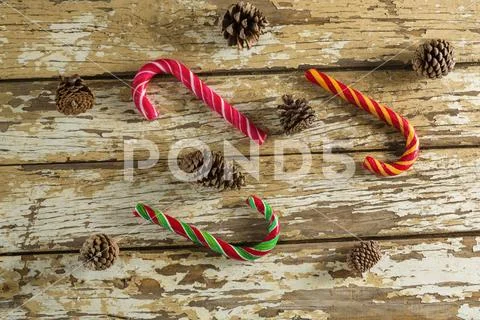 Candy canes and pine cones on wooden plank Stock-Fotos