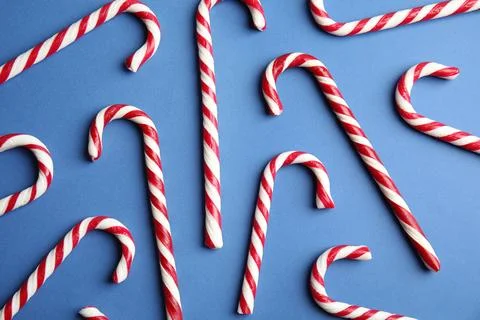 Candy canes on blue background, flat lay Stock Photos