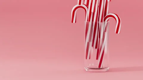 Candy canes fall into a glass on pink background. New Year, Christmas concept Stock Footage 293358906