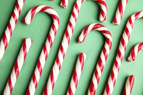 Candy canes on green background, flat lay Stock Photos