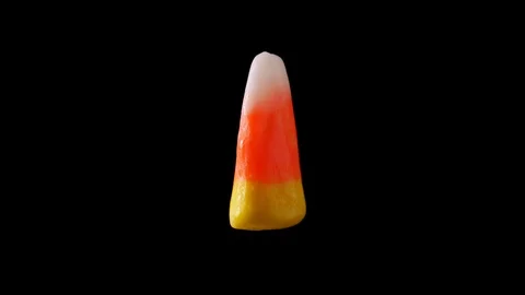 Candy corn is seen floating and slowly rotating with a dark background. Stock Footage 116399737
