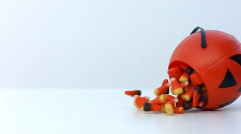 Candy corn spills out of a pumpkin container in slow motion Stock Footage 54637909