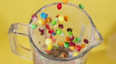 Candy explosion on yellow studio background in blender in slow motion Stock Footage 54669590