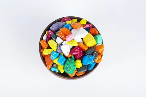 Candy pebbles scattered from small white bowl to coaster on a rustic old burlap Stock Photos
