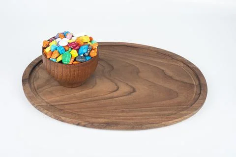Candy pebbles scattered from small white bowl to coaster on a rustic old burlap Stock Photos