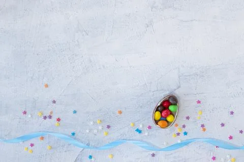 Candy in the shape of an egg filled with multi-colored chocolates on a white Stock Photos