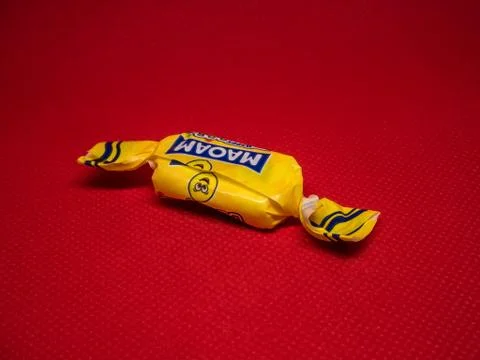 Candy in a yellow wrapper on a red background Stock Photos