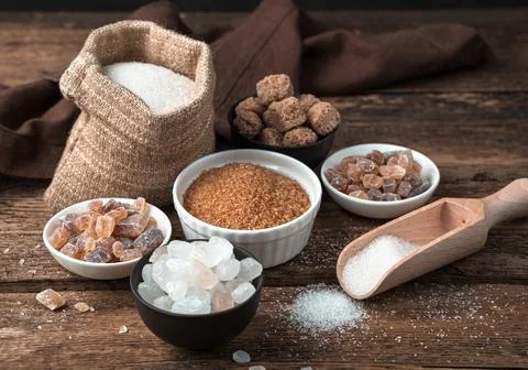 Cane and white sugar in different states on a wooden background. Side view. Stock Photos